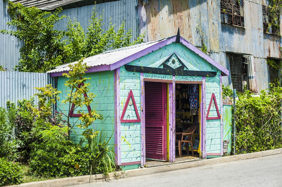 Small turquoise and purple wooden shop with an open door beside a corrugated metal building in Bridgetown, Barbados
