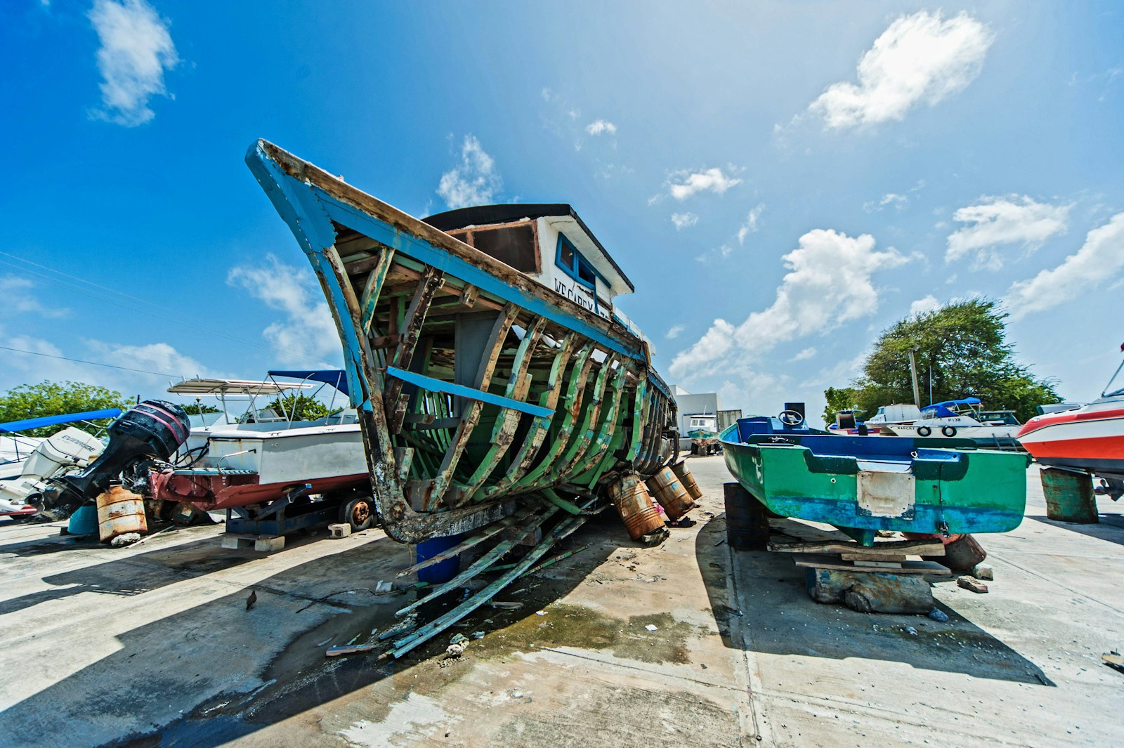 Wooden fishing boat hull being repaired in a boat yard at Hastings, Barbados, beside smaller boats