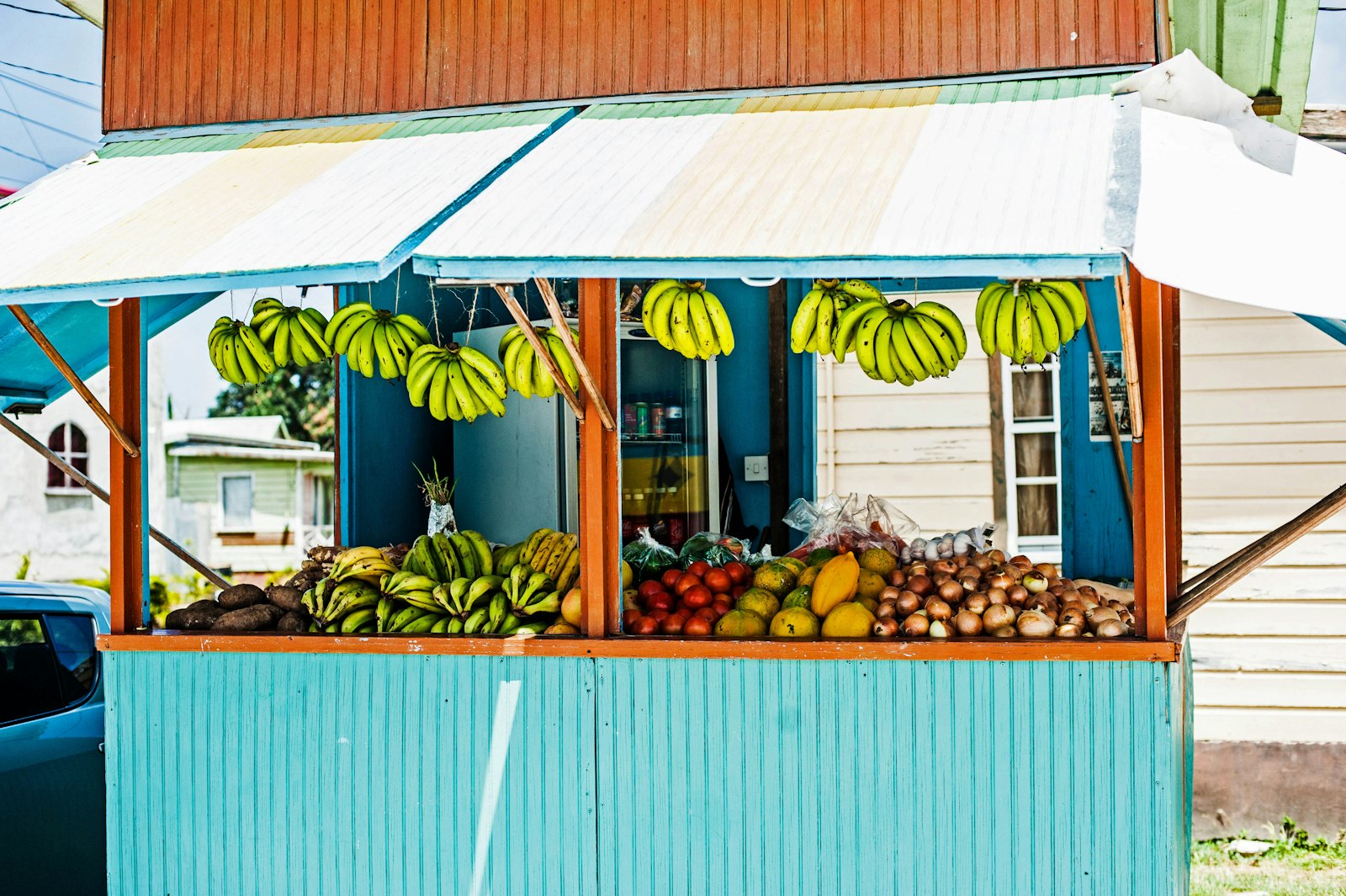Roadside fruit stand with hanging bananas, tomatoes and onions in Hastings, Barbados